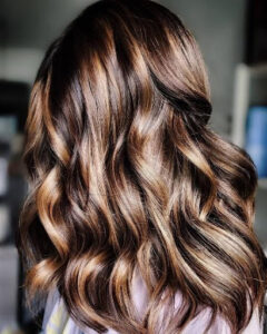 Shiny copper balayage in medium hair length with curls