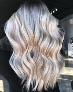 Icy blonde balayage hair with shadow roots in a long and bouncy hair