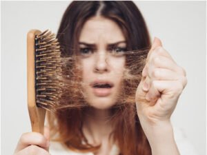 A girl holding a comb with her falling hair stuck in it