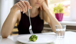 A girl holding a fork with a broccoli